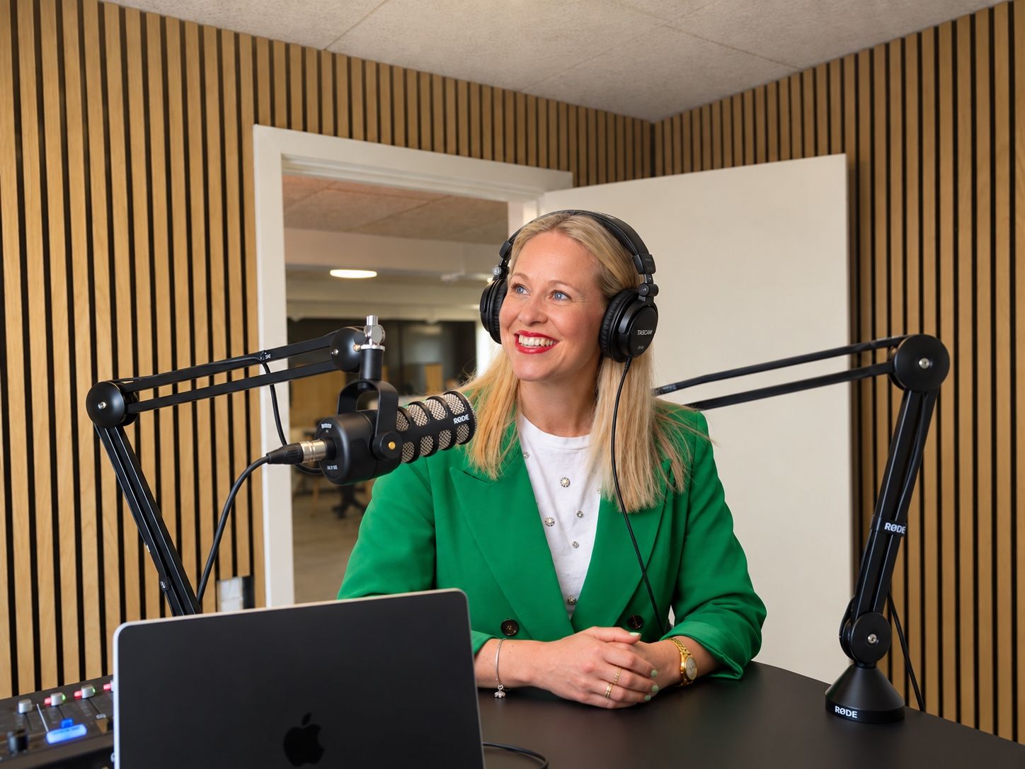 Marie Fink med høretelefoner ved mikrofonen i podcaststudiet